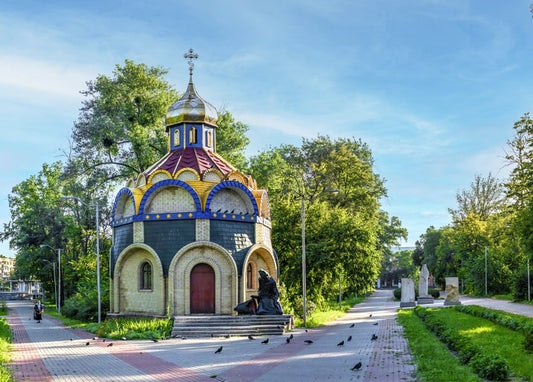Каплиця з кольоровим куполом у парку Черкас, біля входу бронзова постать у скорботі