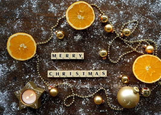 Holzbuchstaben „Merry Christmas“ zwischen Orangenscheiben und goldenen Kugeln
