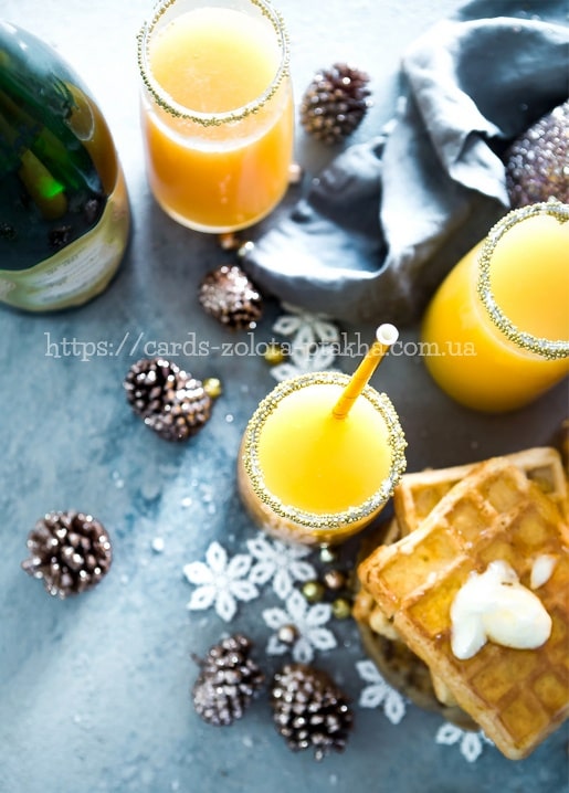 Draufsicht auf Mimosa-Cocktails, Sekt, Tannenzapfen und Waffeln mit Sahne