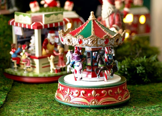Bemaltes Miniatur-Karussell mit Pferden vor Santas beleuchteter Werkstatt