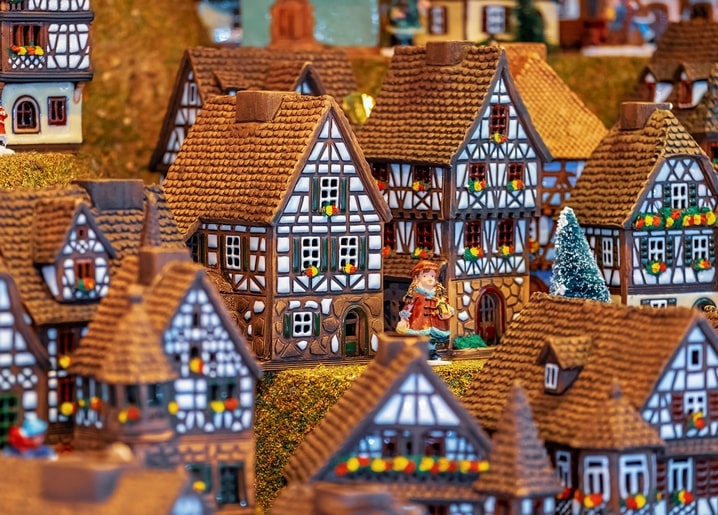 Miniatur-Fachwerkhäuser mit schneebedeckten Dächern und einer kleinen Figur dazwischen