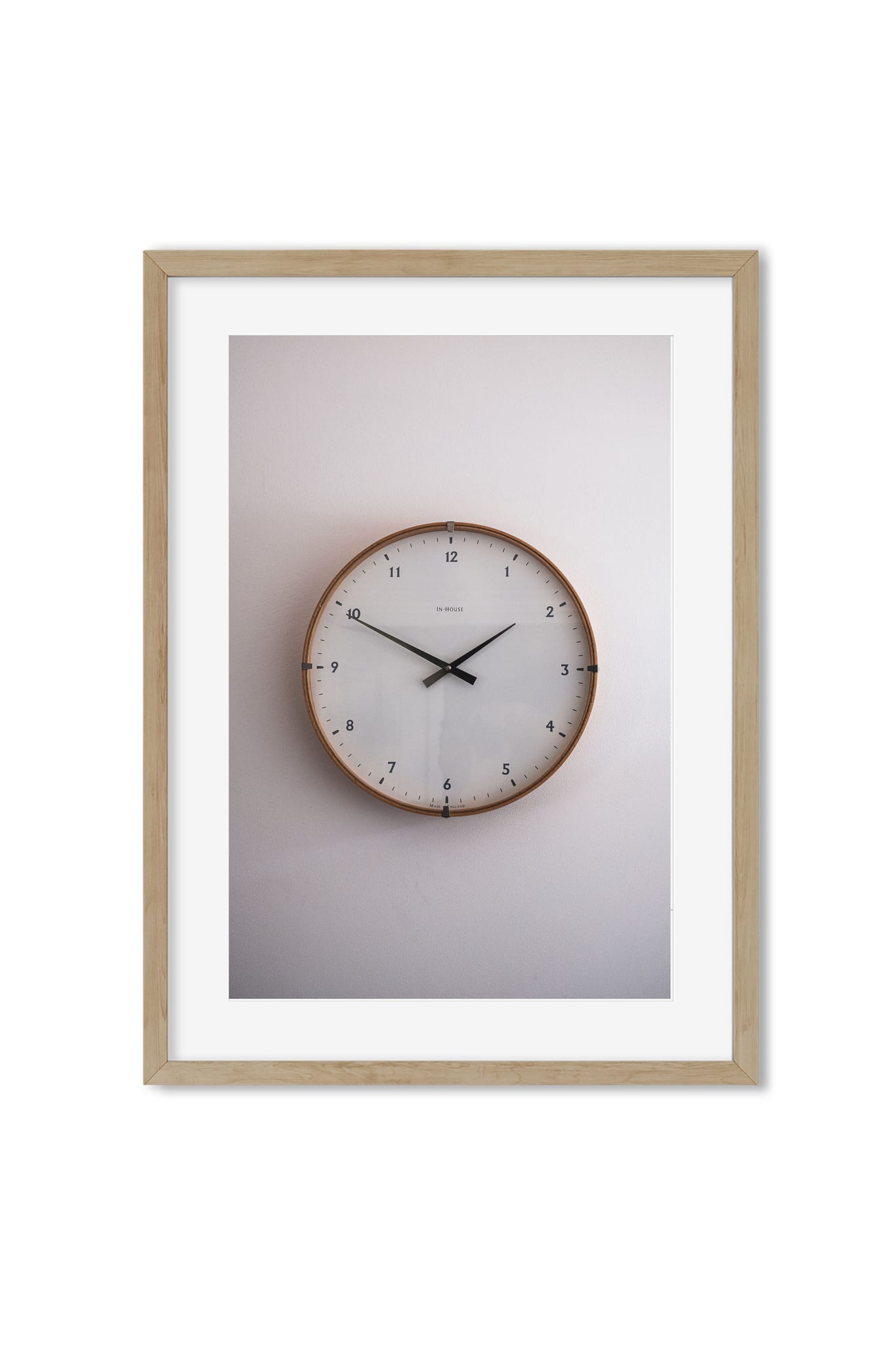Photo poster of a round wooden-framed wall clock against a cream wall in soft light