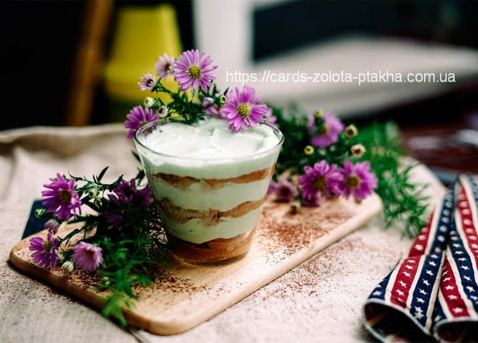 Minz-Schoko-Parfait im Glas mit Kakaostaub und lila Astern auf Holzbrett