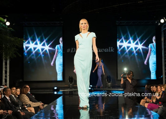 Model in mintfarbenem Kleid auf dem Laufsteg vor sternförmigen LED-Screens
