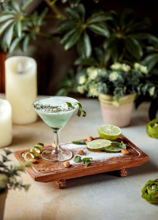 Cocktail mit Salzrand, Limettenzeste, Minze und Mandeln auf Holztablett