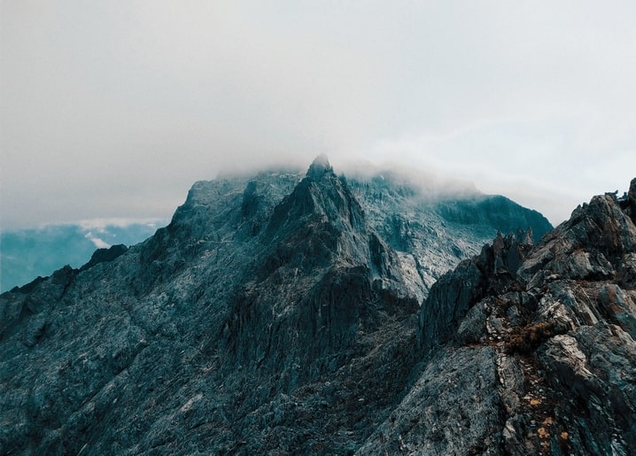 Dunkler felsiger Berggipfel eingehüllt in Wolken und Nebel