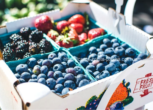 Holzkiste mit frischen Brombeeren, Erdbeeren und Blaubeeren in Papierschalen