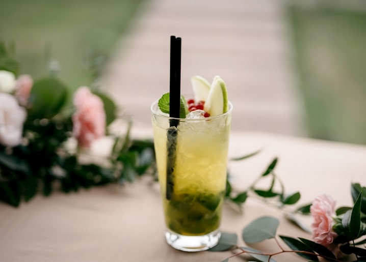 Mojito mit Minze, Limette und Beeren zwischen rosa Blüten