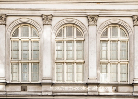 Drei hohe Bogenfenster mit schmiedeeisernen Gittern an einer hellen neoklassizistischen Fassade