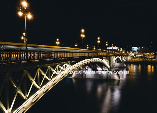 Beleuchtete stählerne Bogenbrücke bei Nacht mit verwischten Lichtspuren vorbeifahrender Fahrzeuge