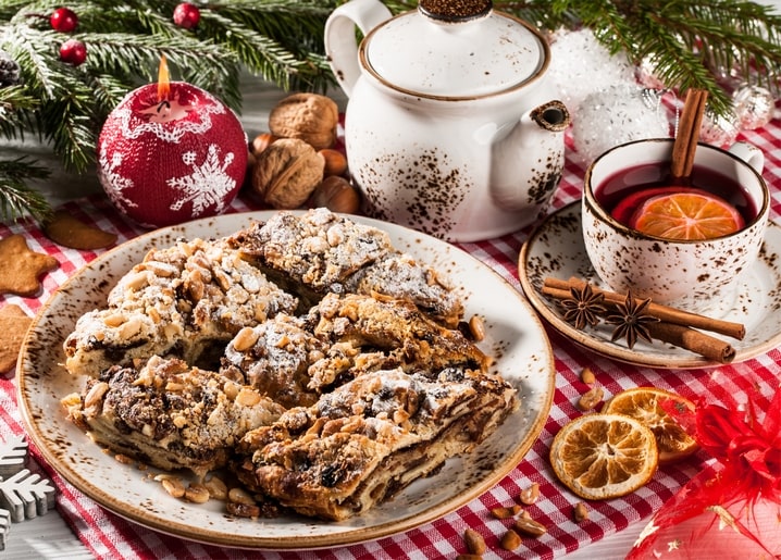Plate of nut pie beside a teapot and a cup of spiced tea with orange and cinnamon