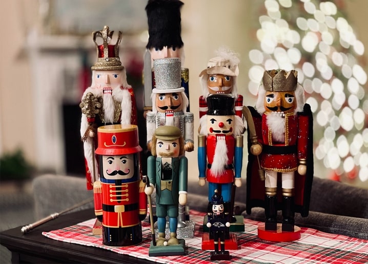 Sammlung hölzerner Nussknacker-Figuren in königlichen und Soldatenkostümen vor einem Weihnachtsbaum