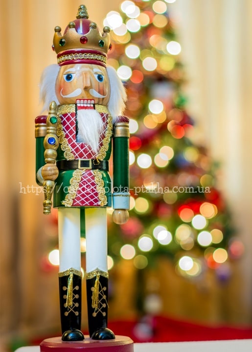 Nussknacker-König mit Krone vor unscharfen Lichtern eines Weihnachtsbaums