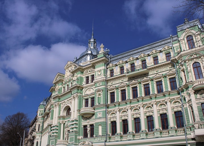 Ornate green and cream building facade in Odesa with balconies and a slender dome