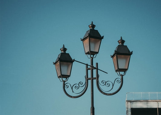 Schmiedeeiserne dreiarmige Straßenlaterne vor klarem blauem Himmel in Odesa