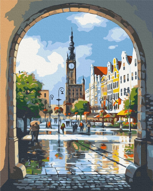 Stone archway framing a rainy old-town square with a clock tower and reflections