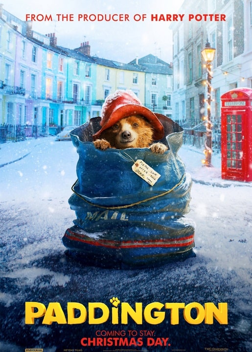 Paddington schaut aus einem Postsack auf einer verschneiten Straße mit roter Telefonzelle