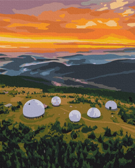 Weiße Radarkuppeln auf einem Hügel unter orangefarbenem Morgenhimmel