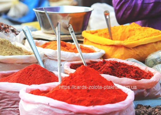 Bags of red paprika and golden turmeric powder with metal scoops at a spice market stall