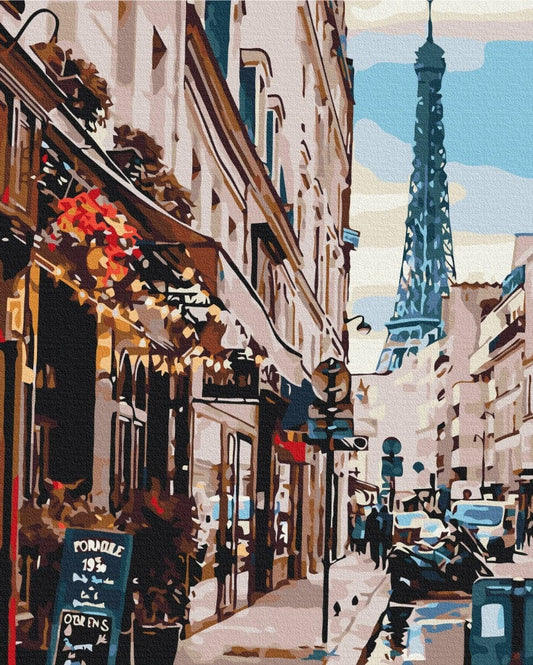 Paris street corner with a café awning strung with lights and the Eiffel Tower rising above the rooftops