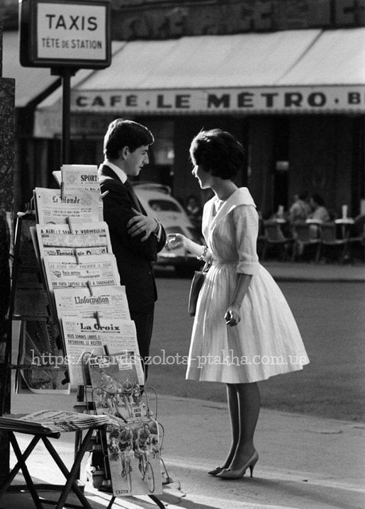 Schwarzweißfoto der 1960er: Paar unterhält sich am Pariser Zeitungskiosk vor einem Café