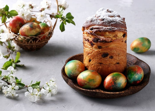 Golden paska dusted with sugar beside marbled Easter eggs and a blooming cherry branch
