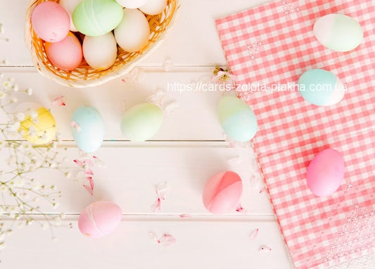 Pastel Easter eggs in a basket beside pink gingham fabric and gypsophila flowers
