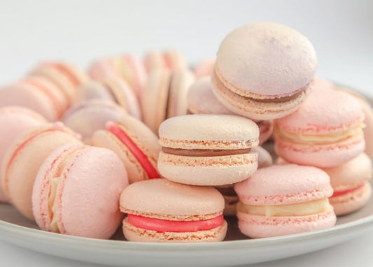 Stack of pastel pink and cream macarons on a white plate, close-up view