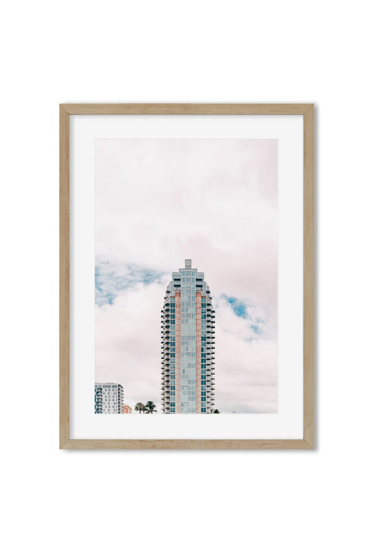 Pastel-colored high-rise building with palm trees against a cloudy sky, poster