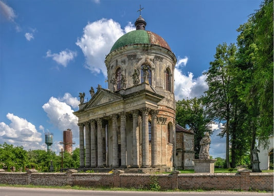 Бароковий костел у Підгірцях з колонадою та скульптурами на тлі літнього неба