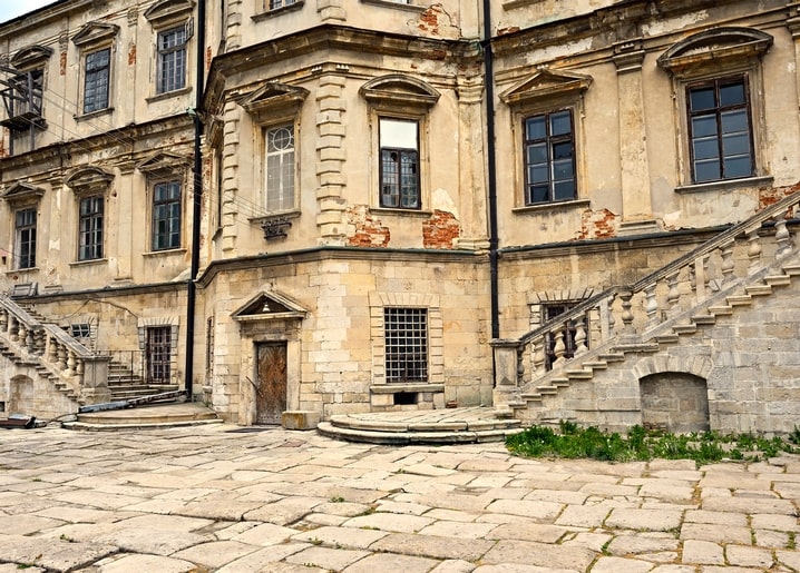 Weathered courtyard of Pidhirtsi Castle with a stone staircase and cracked plaster walls