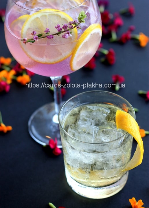 Rosa Cocktail mit Zitrone und Lavendel neben einem Glas mit Zitronenzeste