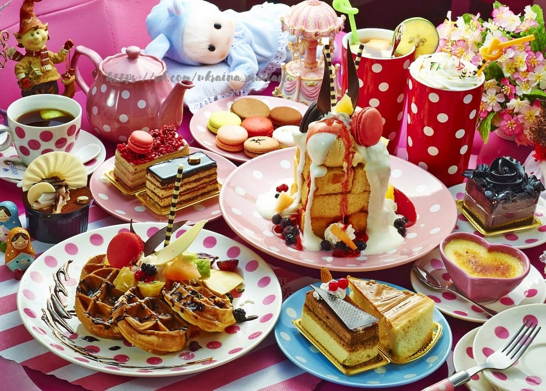 Pinkfarbener Tisch mit Waffeln, Torten, Macarons und einer Teekanne