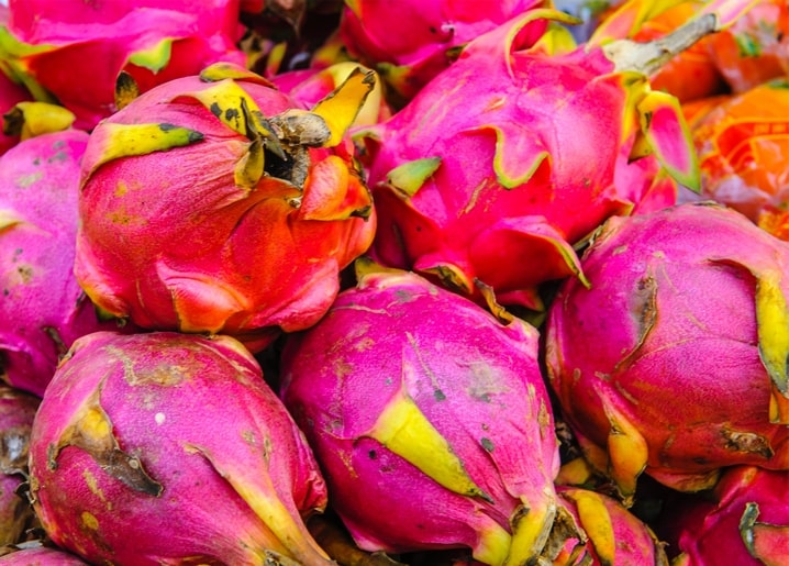 Haufen pinkfarbener Drachenfrüchte mit gelb-grünen Spitzen