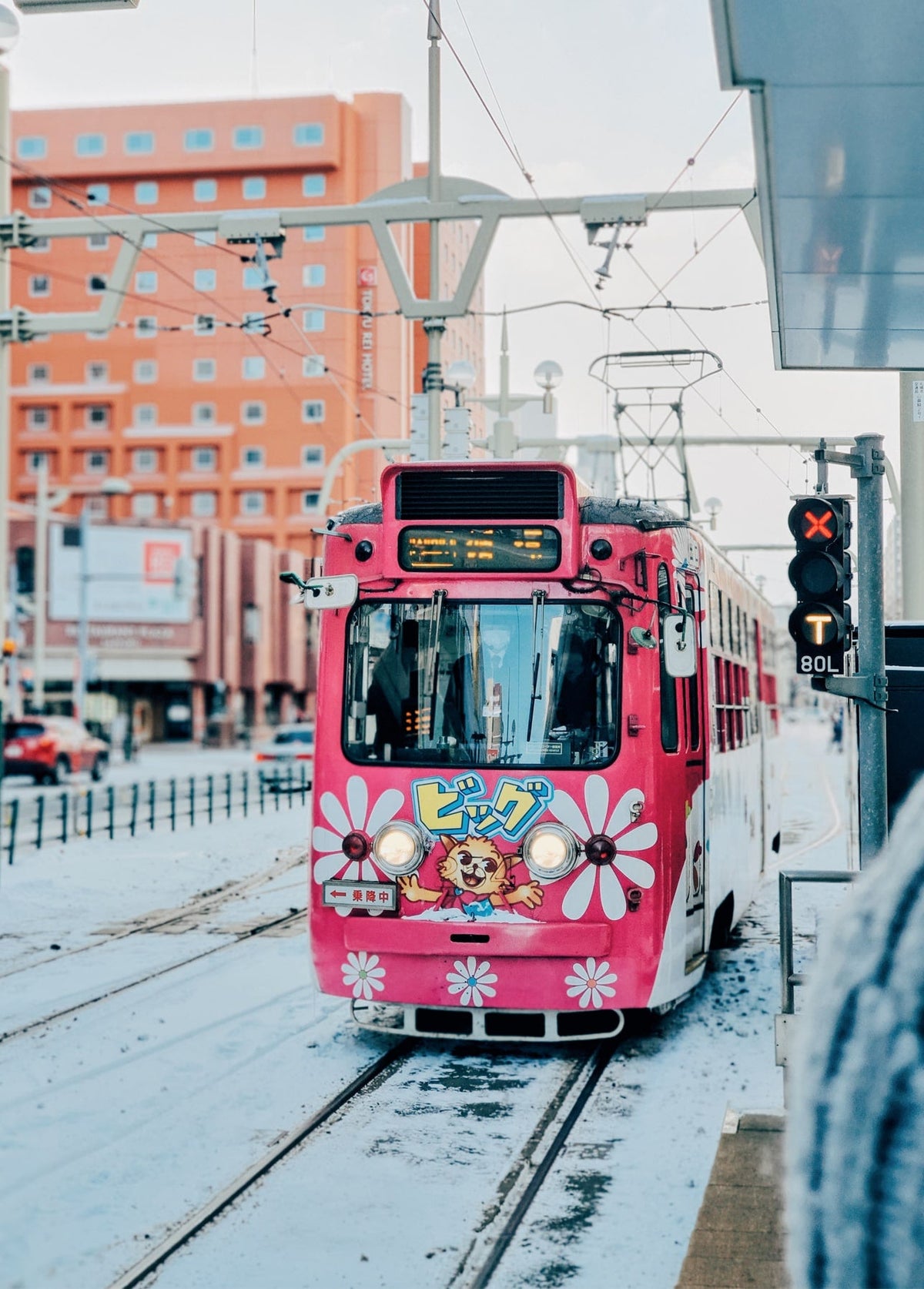 Pink tram decorated with painted flowers on a snowy city street