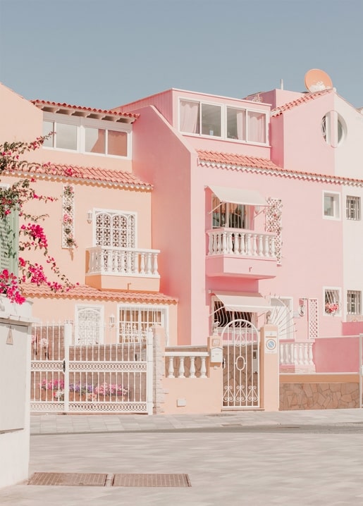 Pastellrosa Haus mit weißen Balkonen und rosa Blumen