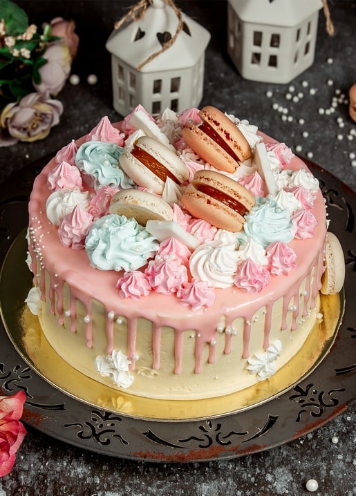 Rosa Drip-Cake mit Macarons, Baiserküssen und kleinen Laternenhäuschen