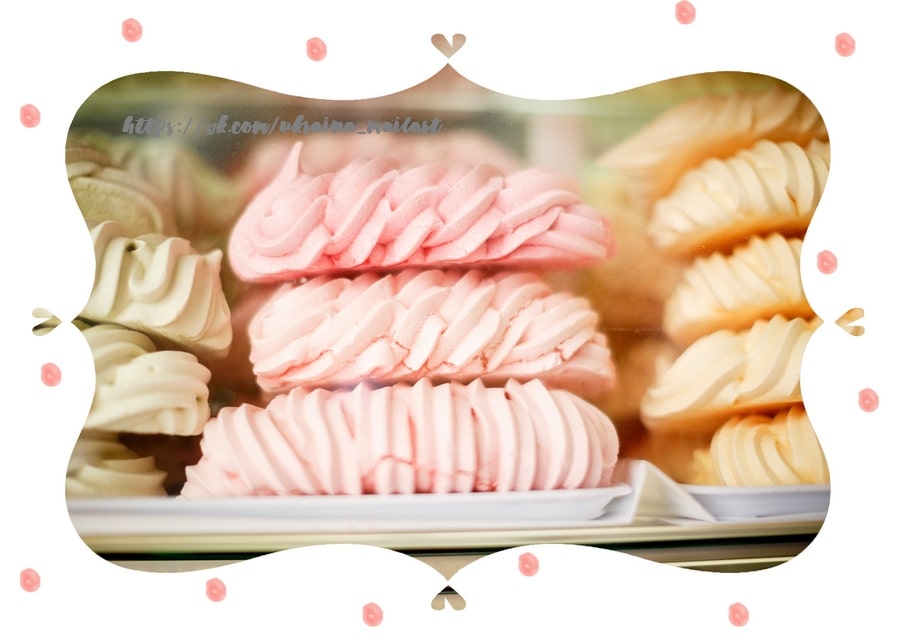 Three ridged pink meringues stacked in a bakery glass display case