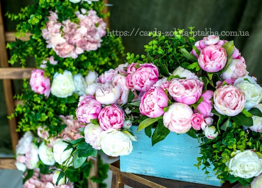 Rosa und weiße Pfingstrosen in verwitterter blauer Holzkiste mit rankendem Grün.