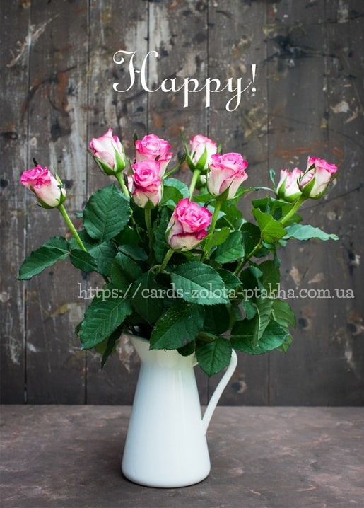 Strauß rosafarbener Rosen in einer weißen Keramikkanne vor einer verwitterten Holzwand