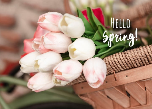 Pink and white tulips in a wicker bicycle basket with red blooms and a Hello Spring script overlay