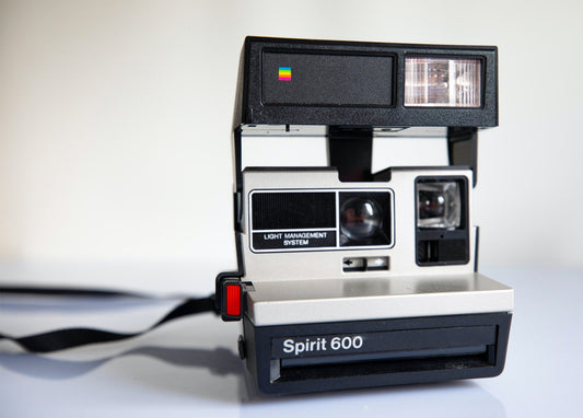 Schwarz-silberne Polaroid Spirit 600 Sofortbildkamera mit hochgeklapptem Blitz und Trageriemen