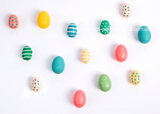 Colorful polka-dot and striped Easter eggs scattered on a white background
