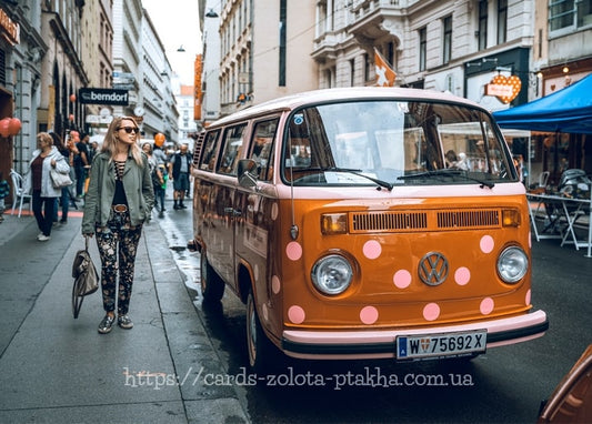 Orange polka-dot VW camper van parked on a Vienna street as a woman walks by