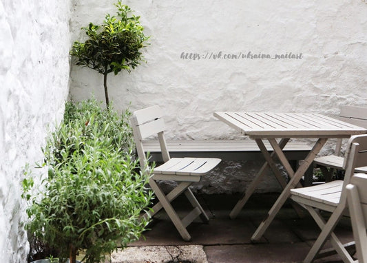 Getopftes Formgehölz und Lavendel neben einem Klapptisch in einem weißen Innenhof
