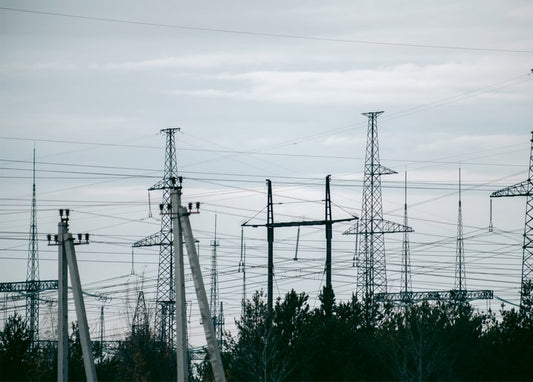 Steel power line pylons in silhouette against an overcast grey sky