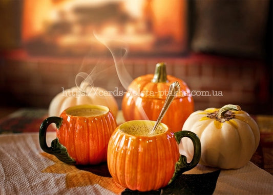Two pumpkin-shaped mugs with steaming drink beside a fireplace and decorative pumpkins