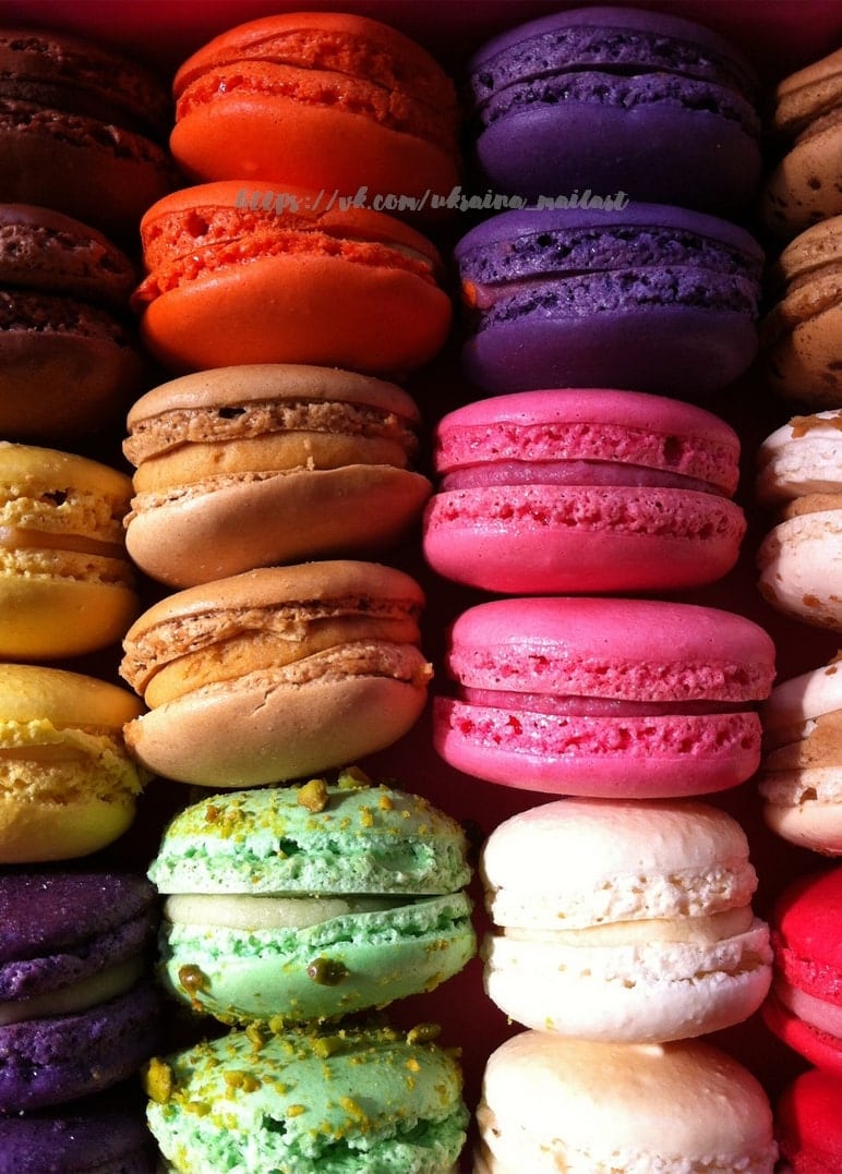 Rows of colorful macarons in orange, purple, pink, mint, and cream