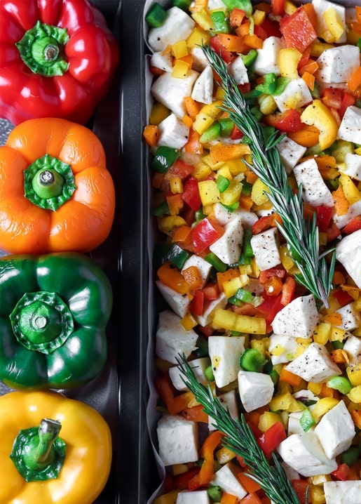 Bunte Paprika neben einem Salat aus gewürfelter Paprika, Mozzarella und Rosmarin