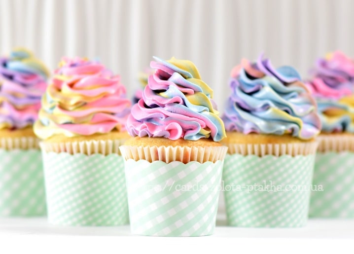Cupcakes mit pastellfarbenen Regenbogen-Cremeschwüngen im mintgrünen Karo-Papier